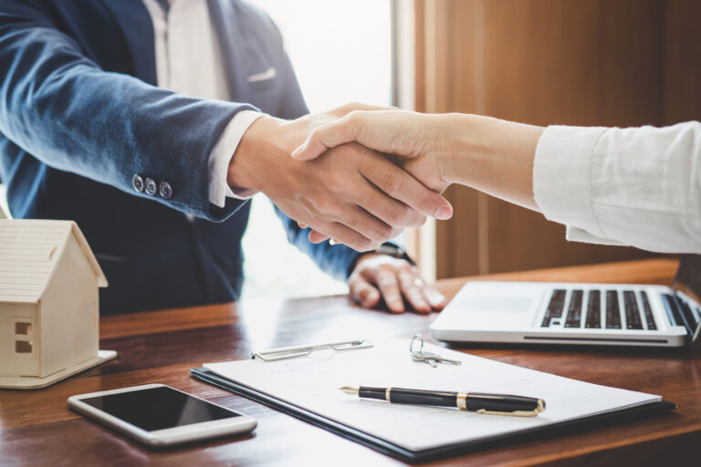 Homebuyer shaking hands with real estate professional after reaching an agreement