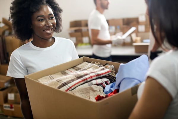 Declutter Your Home: Where to Donate Items in Oak Ridges & the GTA A volunteer happily donating a box of household goods, showcasing stress-free home organization and decluttering before moving.